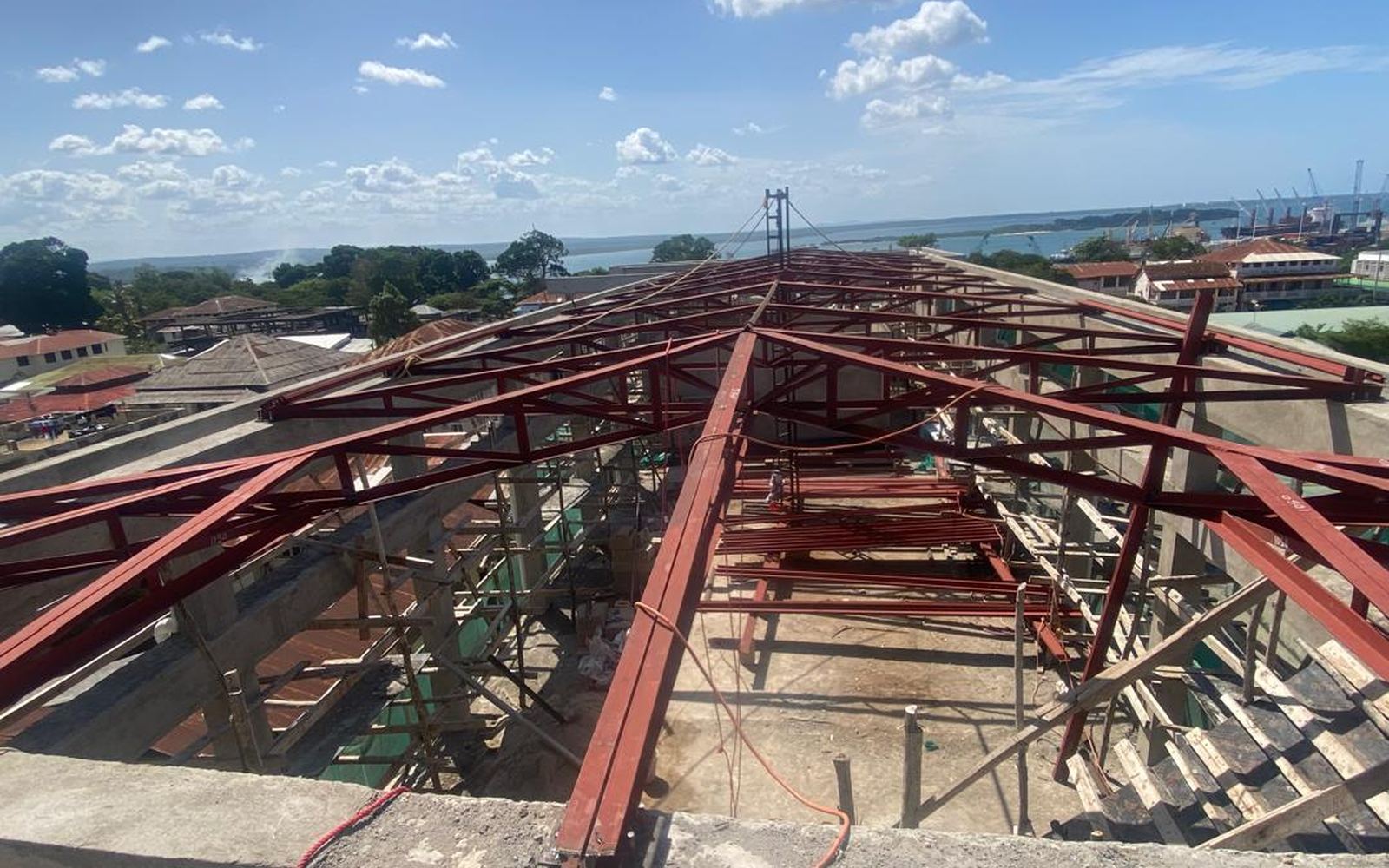 Structural steel roof trusses erected on the TRA Tanga building, with Tanga harbour beyond