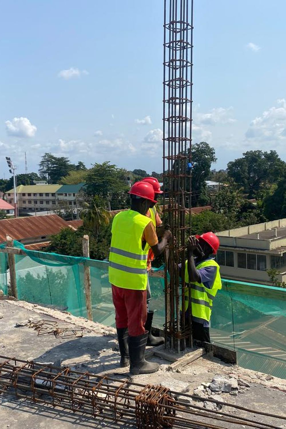Two steel fixers tying column reinforcement cages on the roof slab