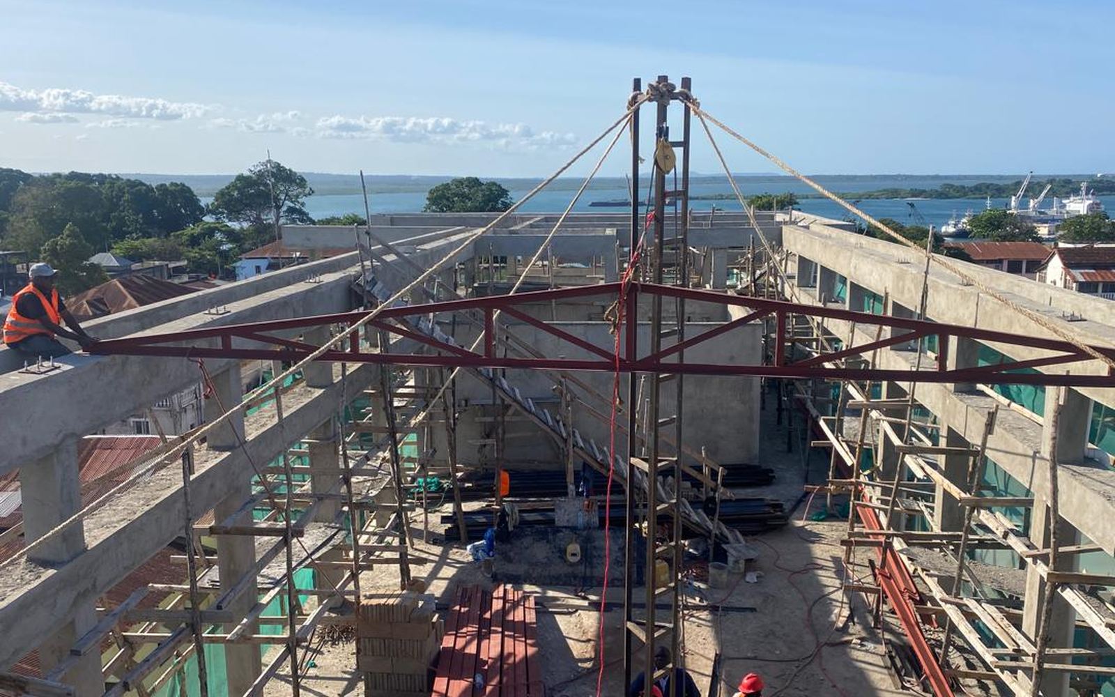 Site team lifting a fabricated steel truss into position over the concrete frame