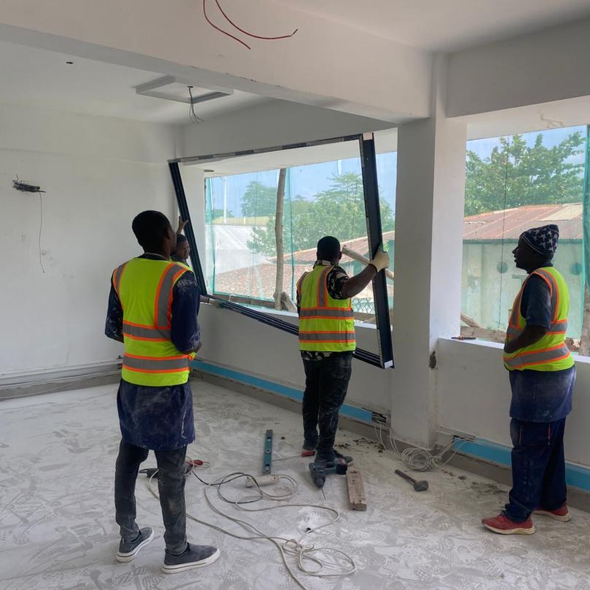 Three workers installing an aluminium window frame in a finished office