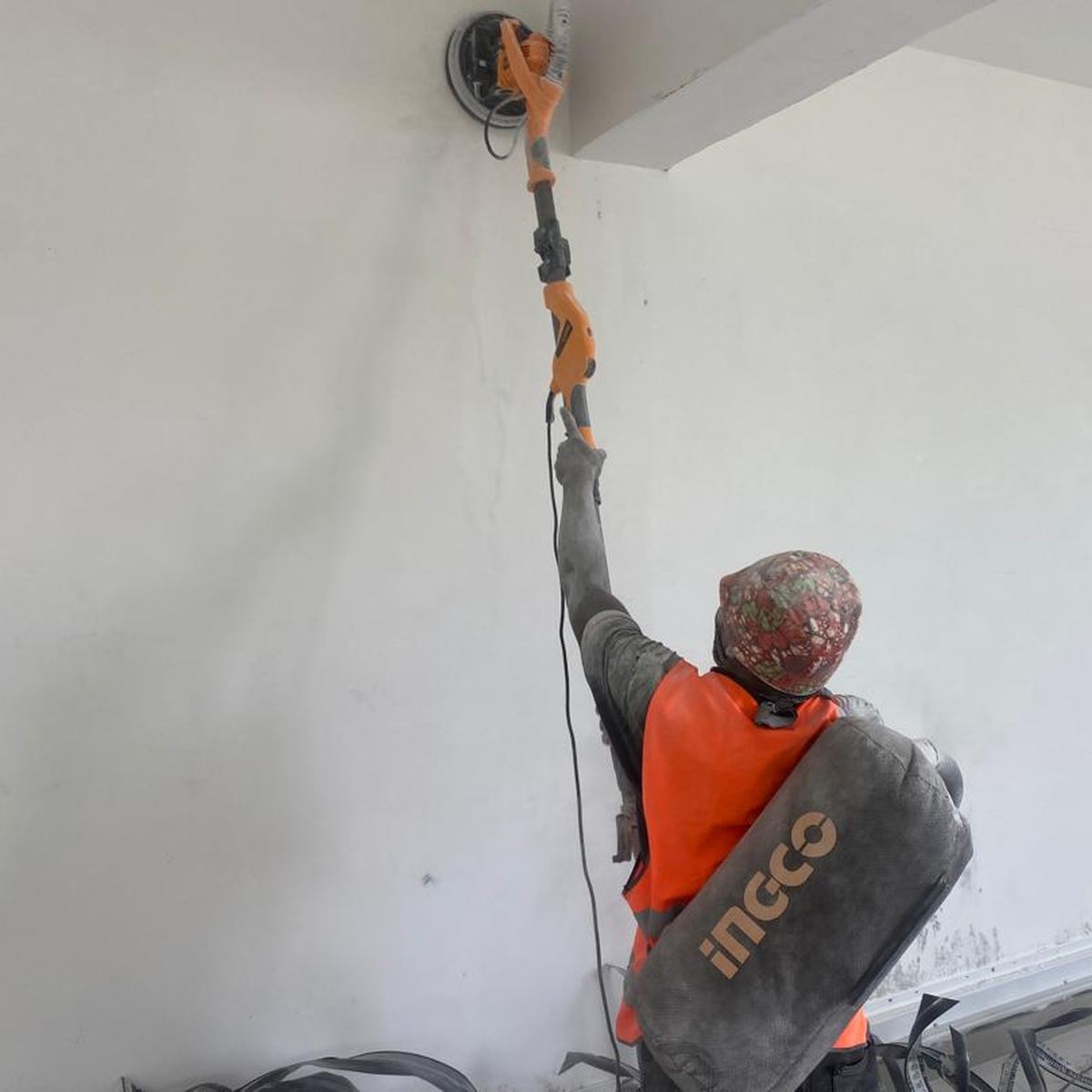 A worker sanding a ceiling with a long-reach sander before painting